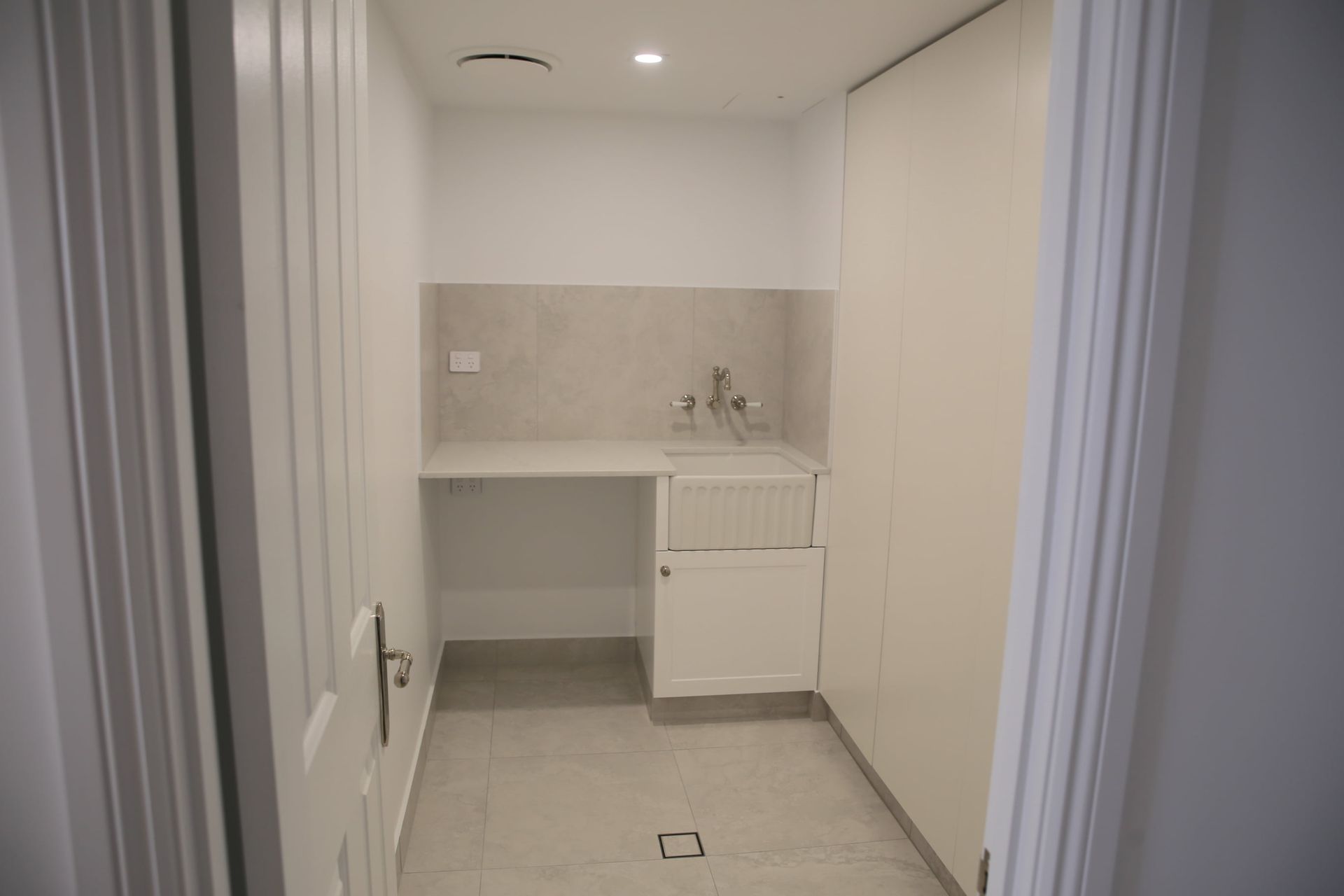 Laundry room with a sink, built-in storage, and neutral-colored walls and floor.