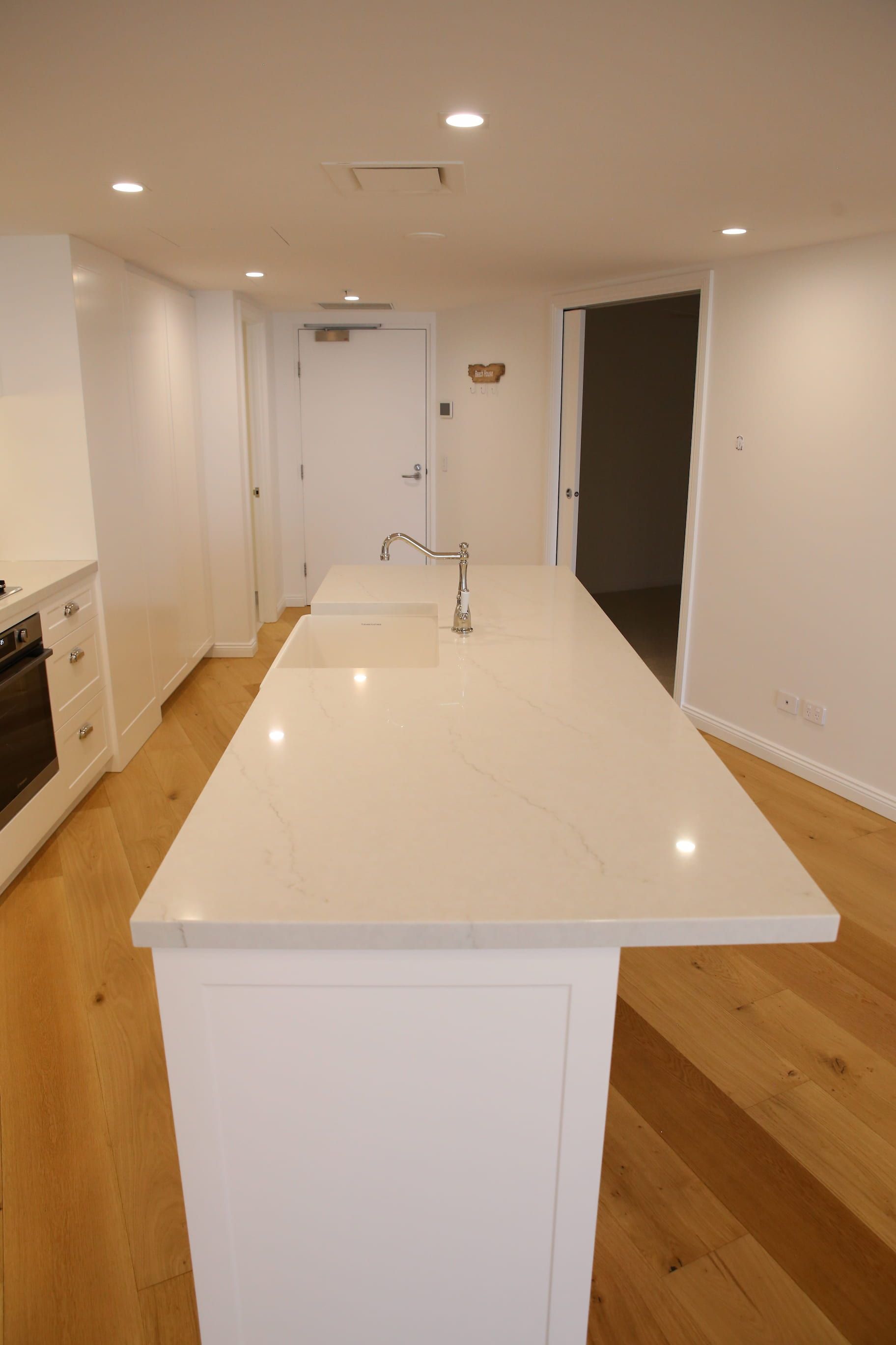 White kitchen with large island, light wood floors, and recessed lighting.