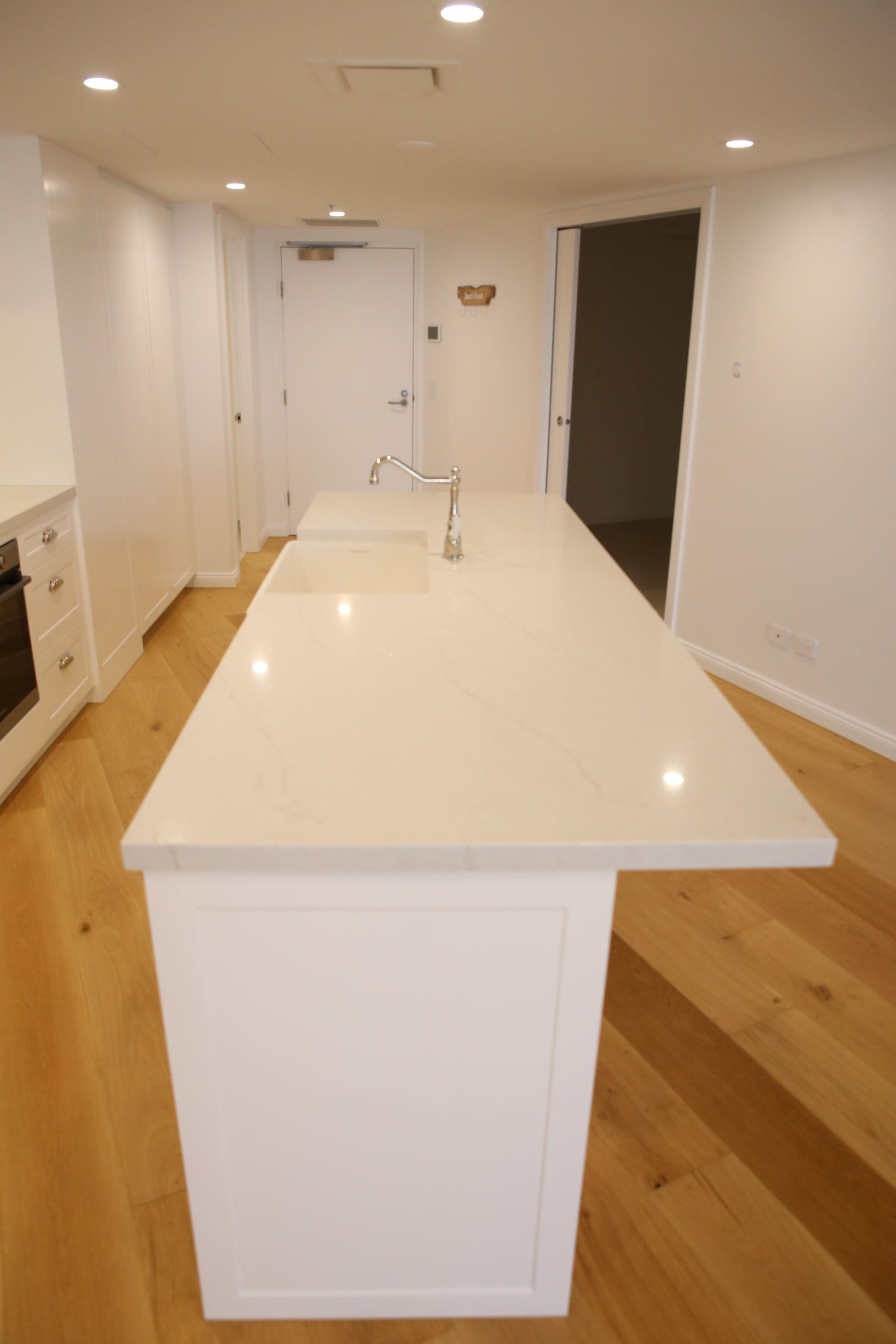 White kitchen island with a sink in a room with hardwood floors.