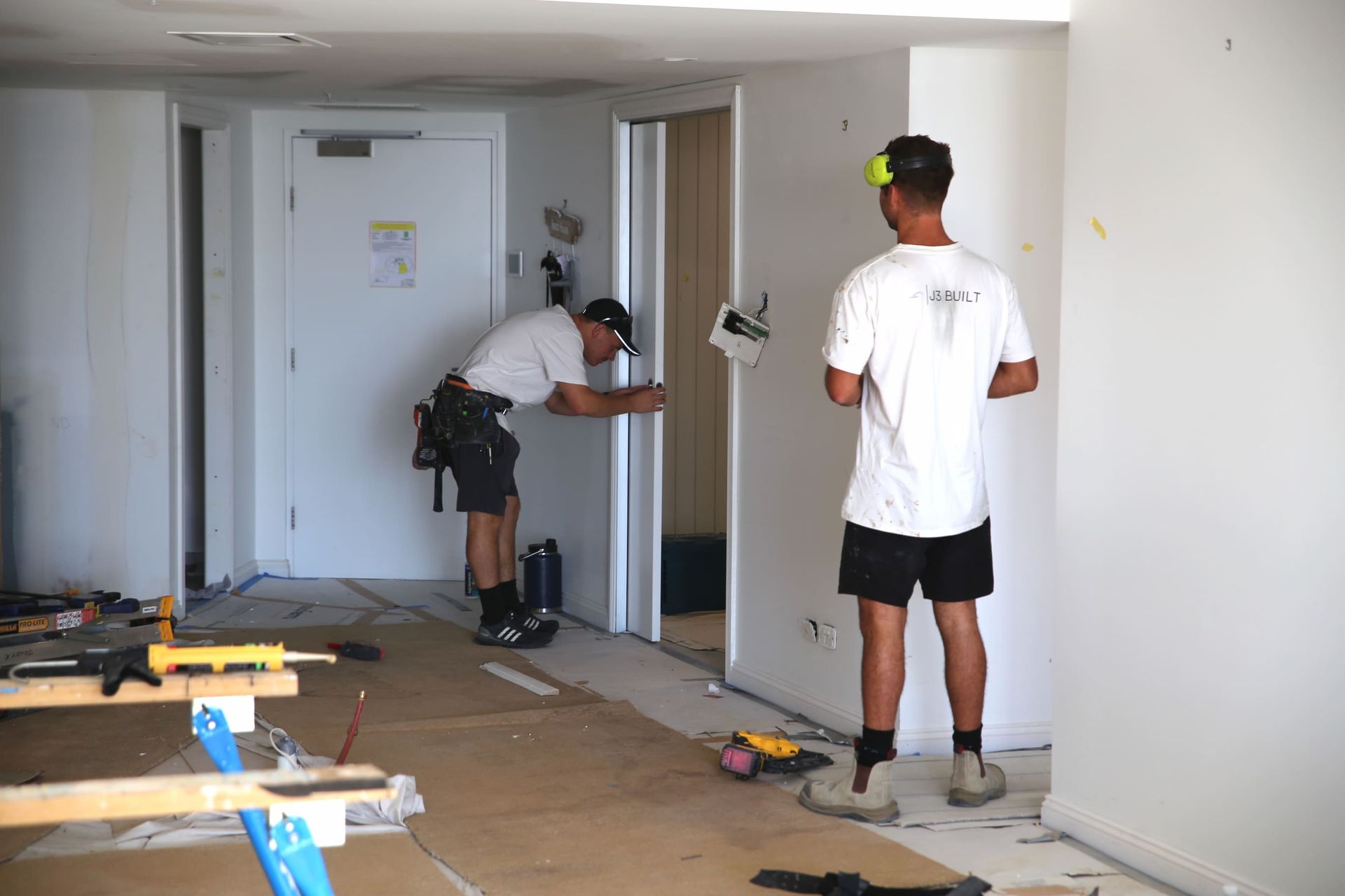 Two workers installing a door in a room under renovation.