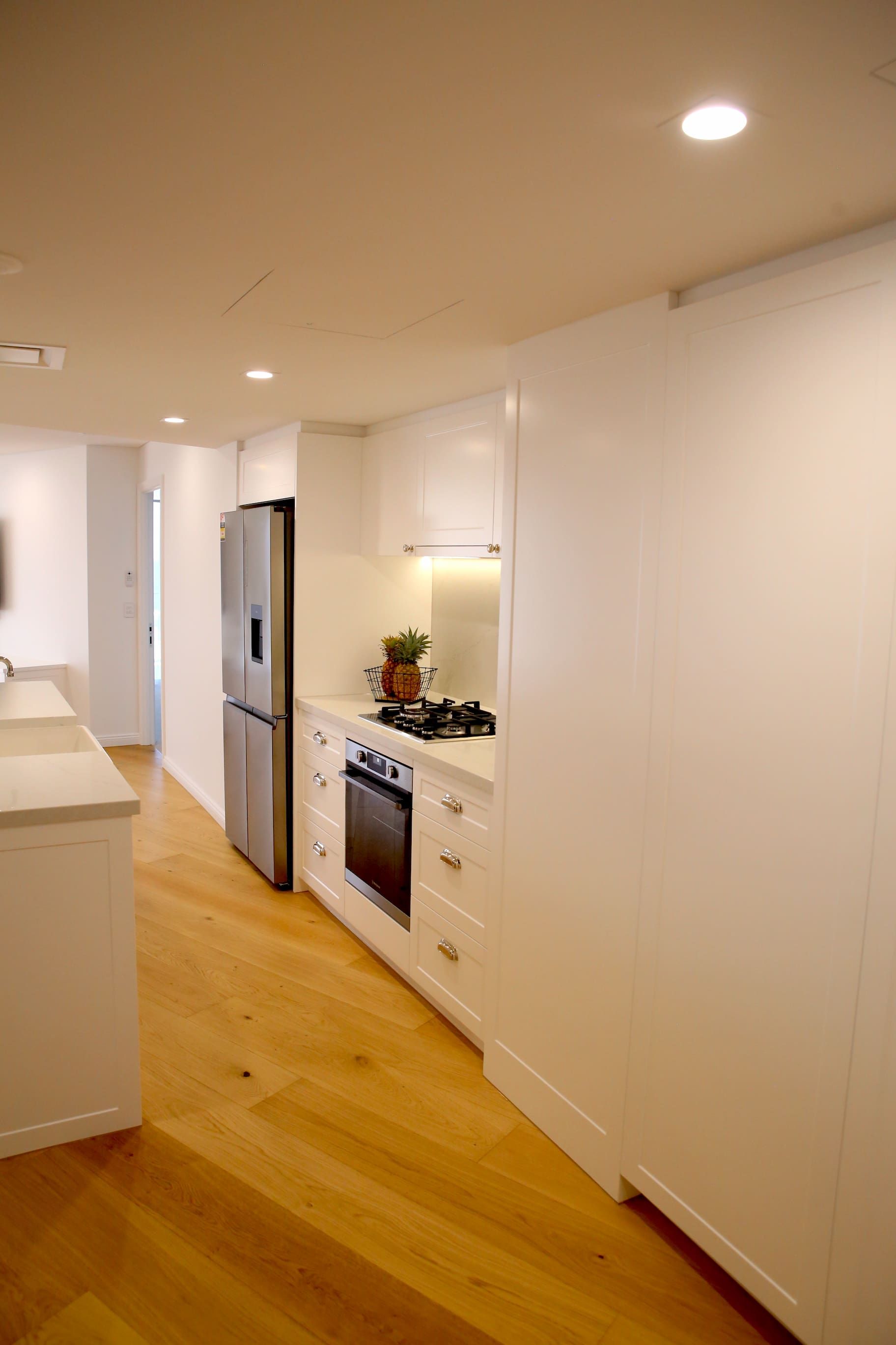 Kitchen with white cabinets, stainless steel refrigerator, gas stove, and hardwood floor.
