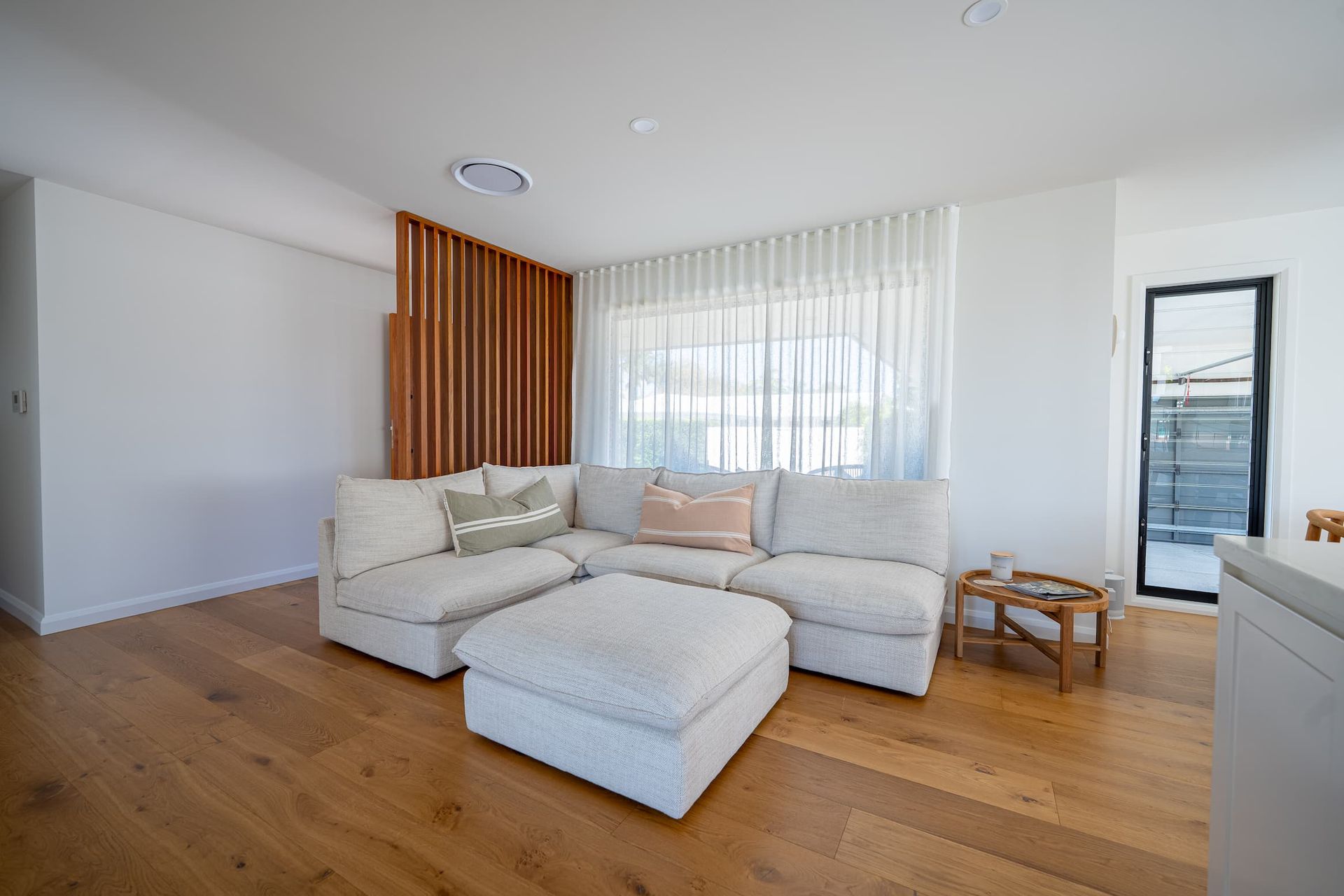 Living room with white sectional sofa, wooden floor, and wooden slatted wall.