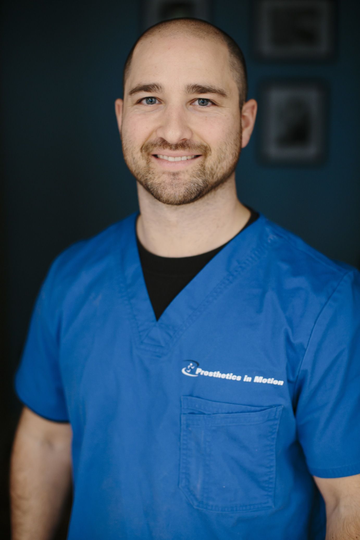 A man in a blue scrub is smiling for the camera