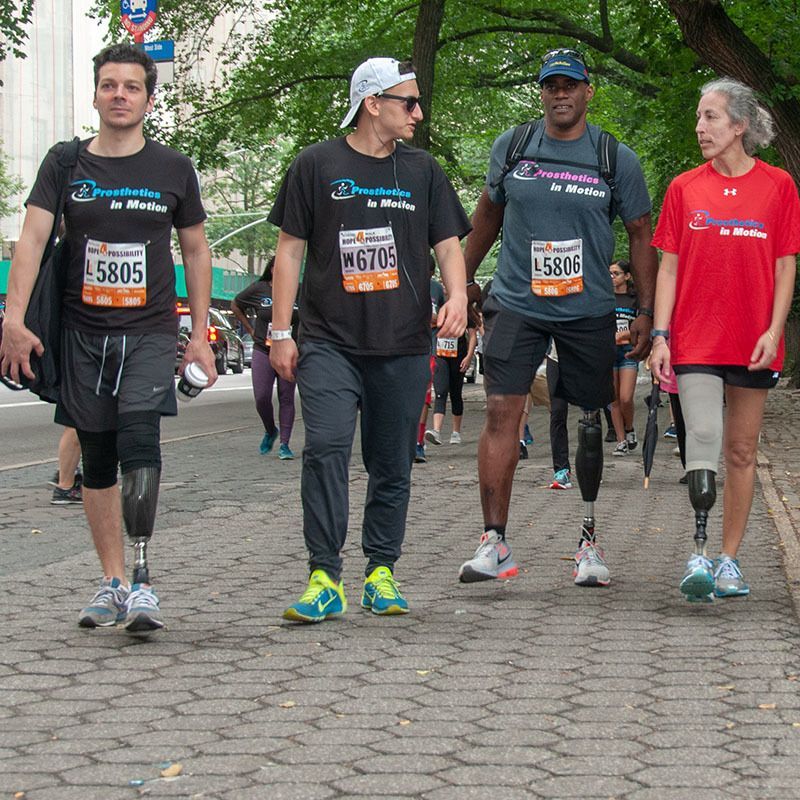 A group of people with prosthetic legs are walking down a sidewalk