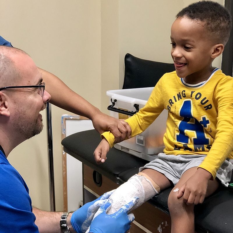 A young boy wearing a yellow shirt that says