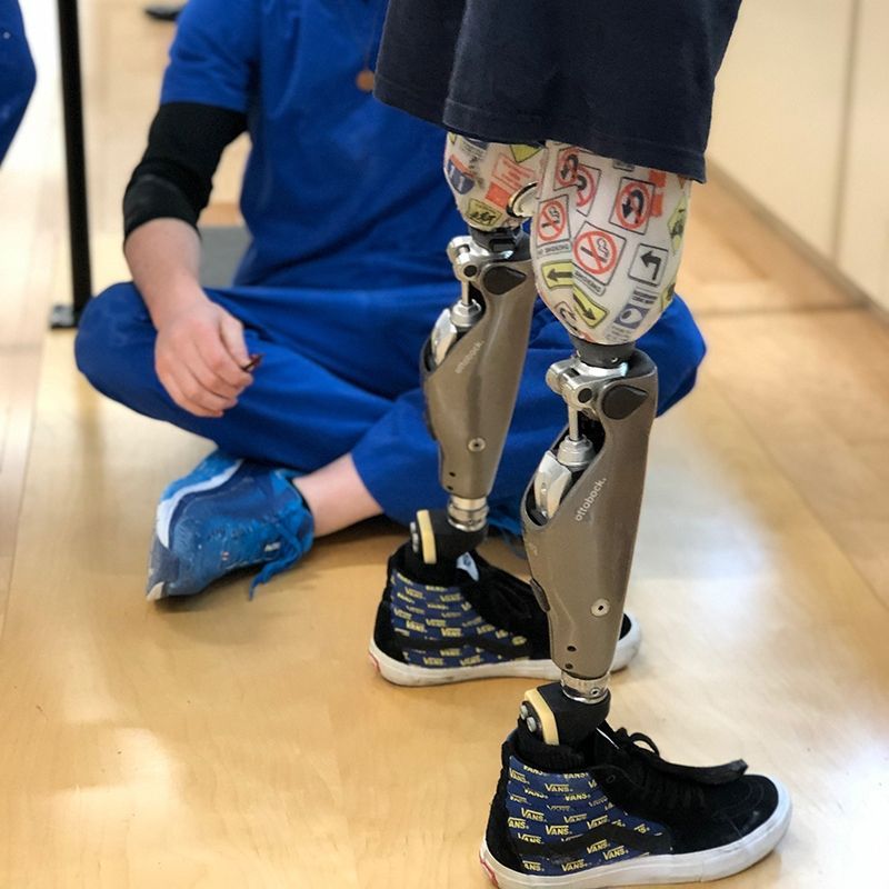 A person with a prosthetic leg is sitting on the floor