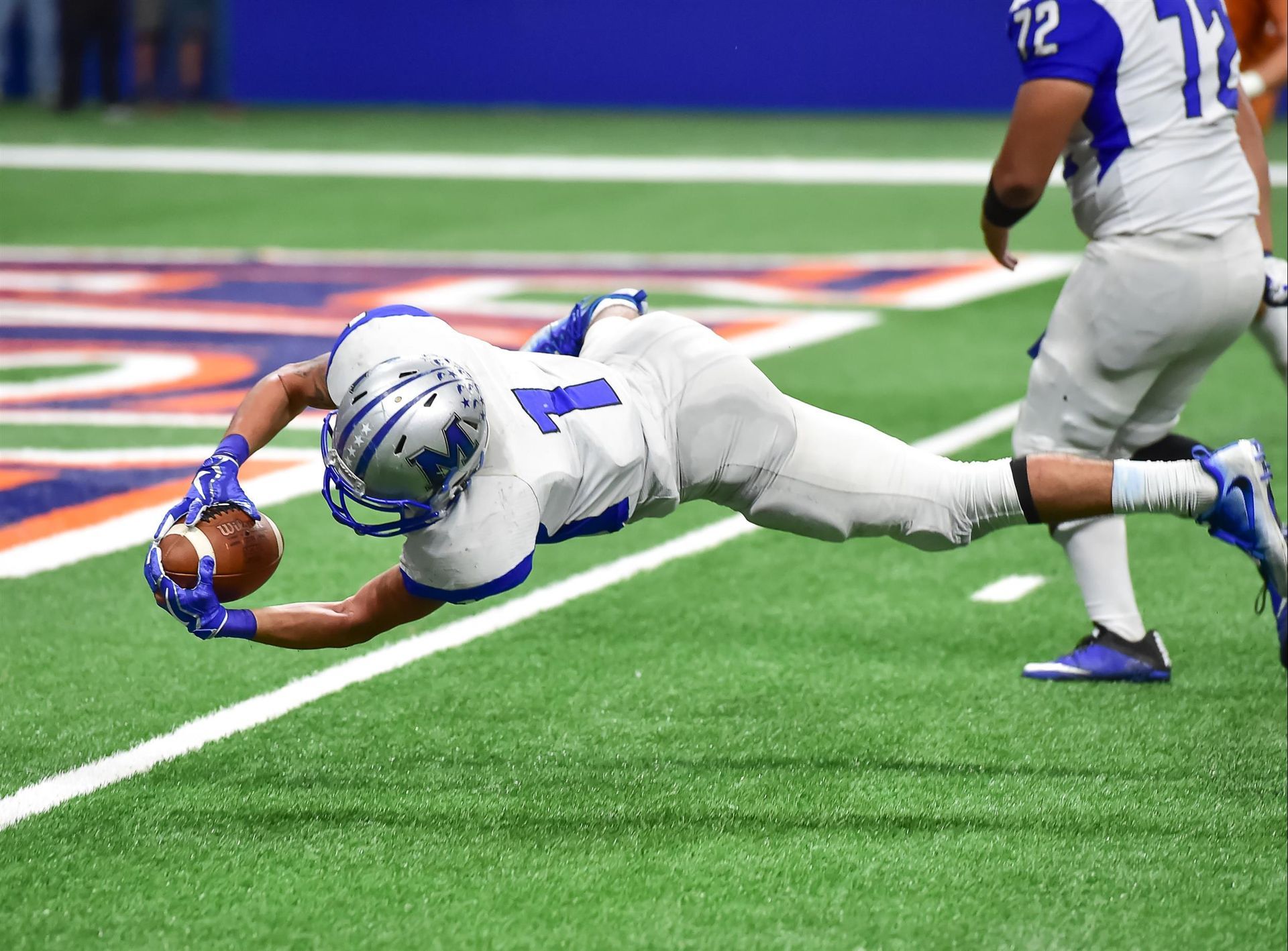 A football player is diving for the ball on the field.