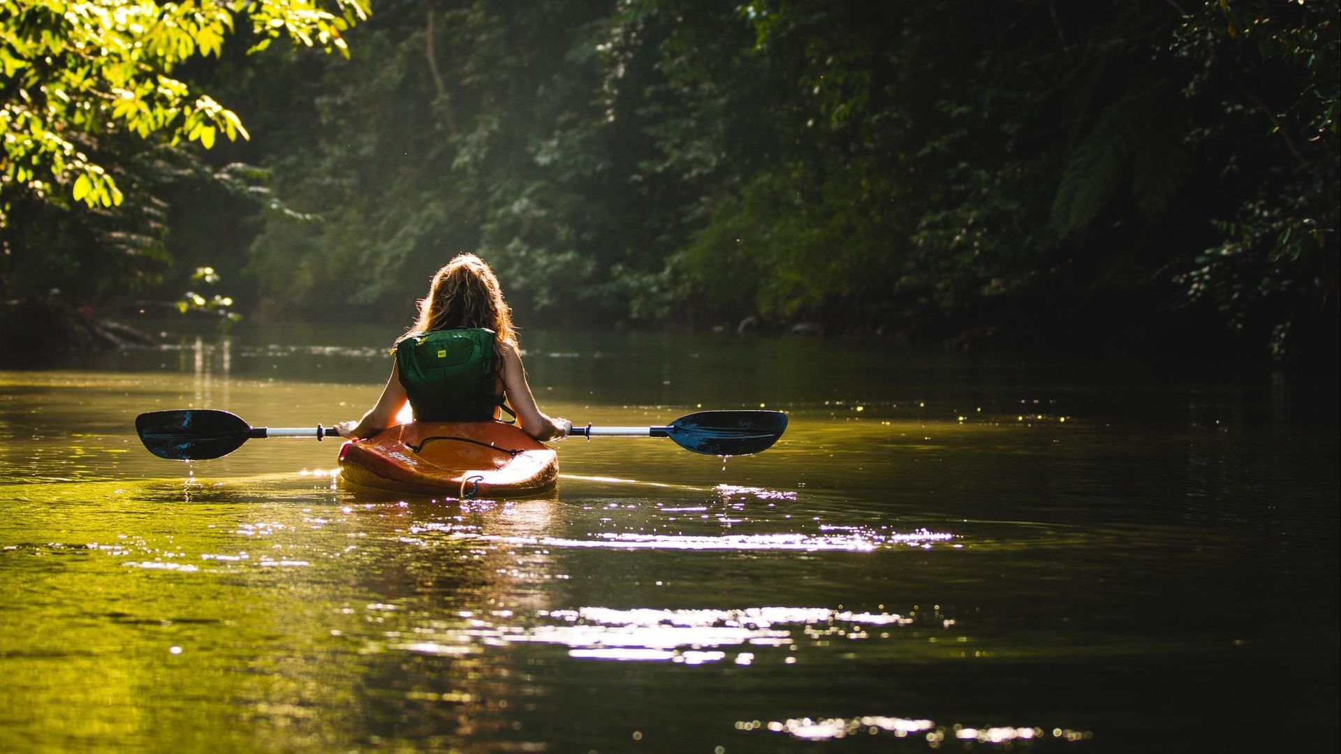 A woman is sitting in a kayak on a river.