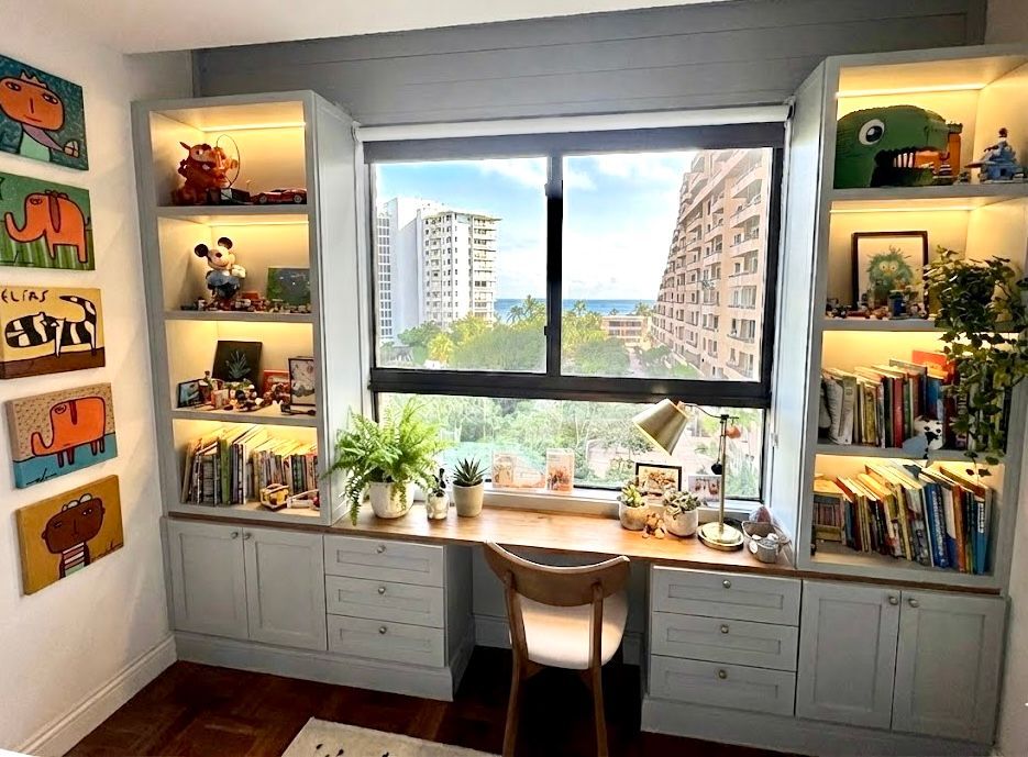 Cozy home office with desk, chair, bookshelf, armchair, and window with wreath. Yellow rug.