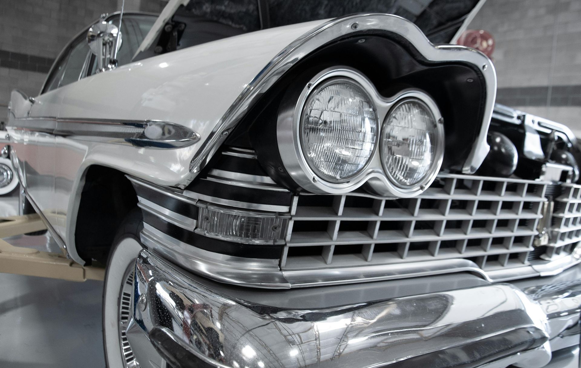 Close-up of a classic chrome car front with twin round headlights and a gleaming grille
