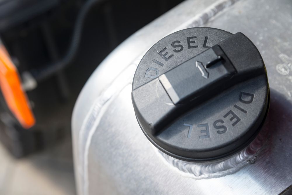 Close-up of a diesel fuel cap on a metal tank with the word “DIESEL” embossed on it