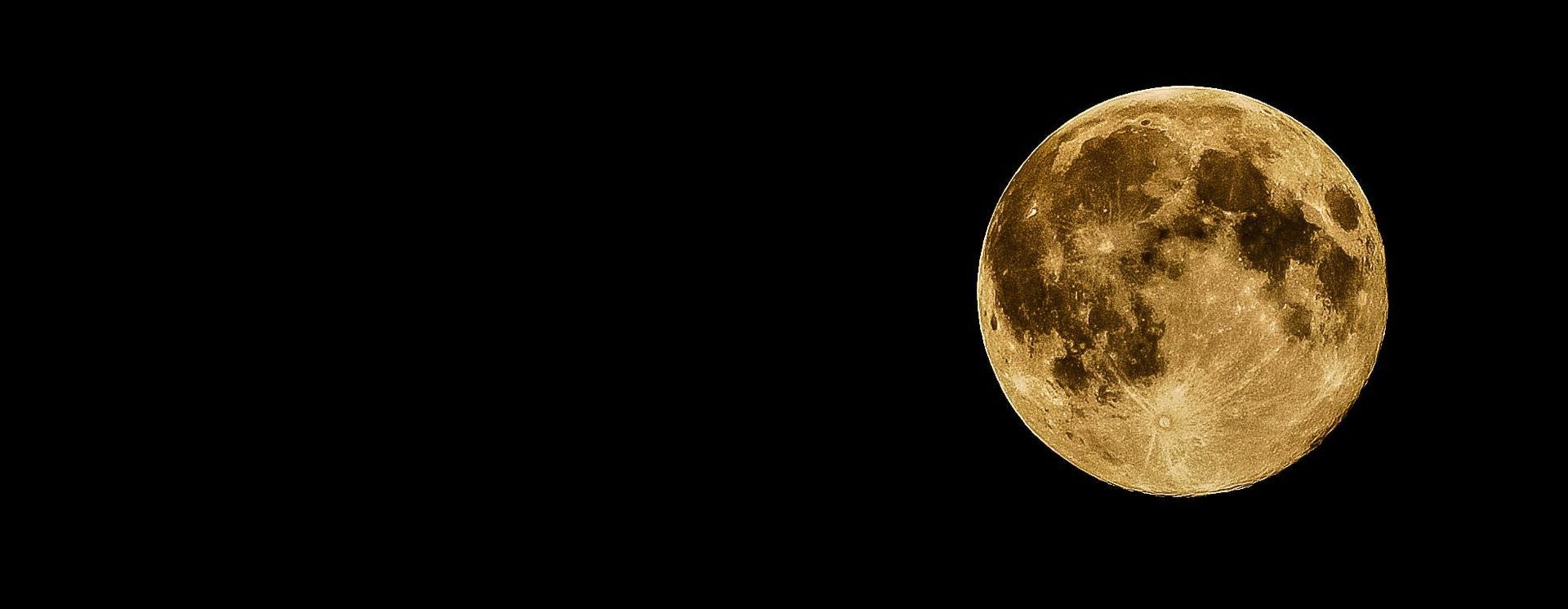 Luna llena dorada contra un cielo nocturno negro.
