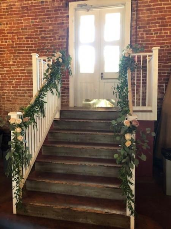 Flower-decorated staircase leading to a white door against a brick wall