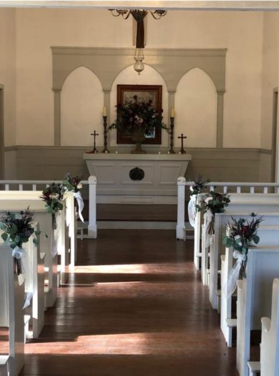 Decorated church aisle leading to an altar with white flowers and candles