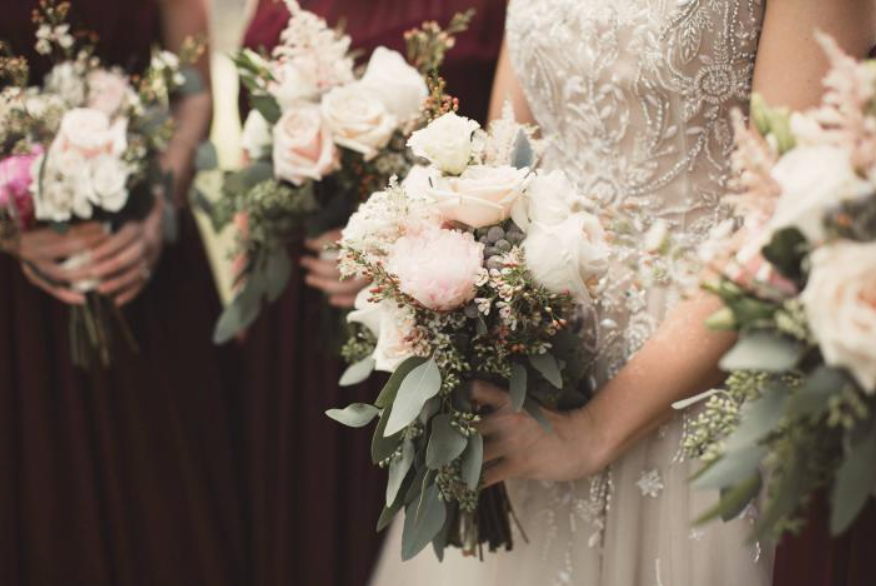 Bridal bouquets of pale pink and white flowers held by women in elegant dresses