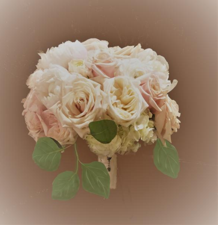 Bouquet of pale pink and cream roses with green leaves on a soft brown background
