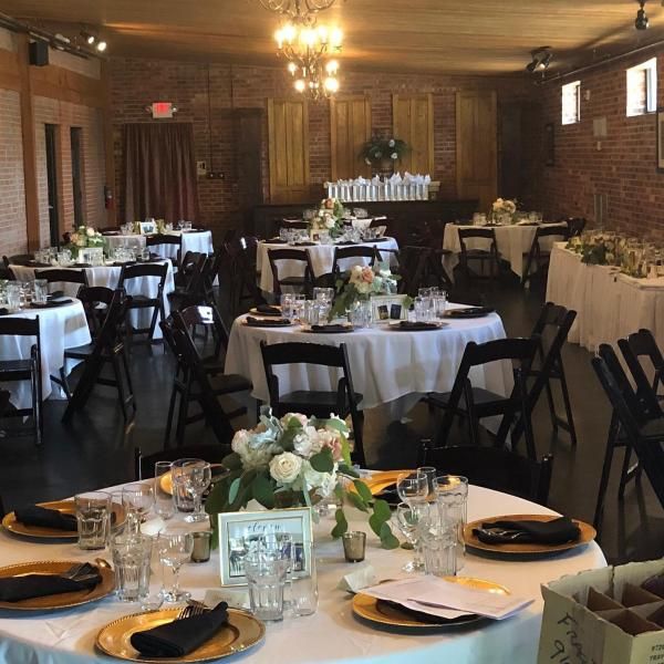 Banquet hall with round tables set for a formal event, white tablecloths, and floral centerpieces.