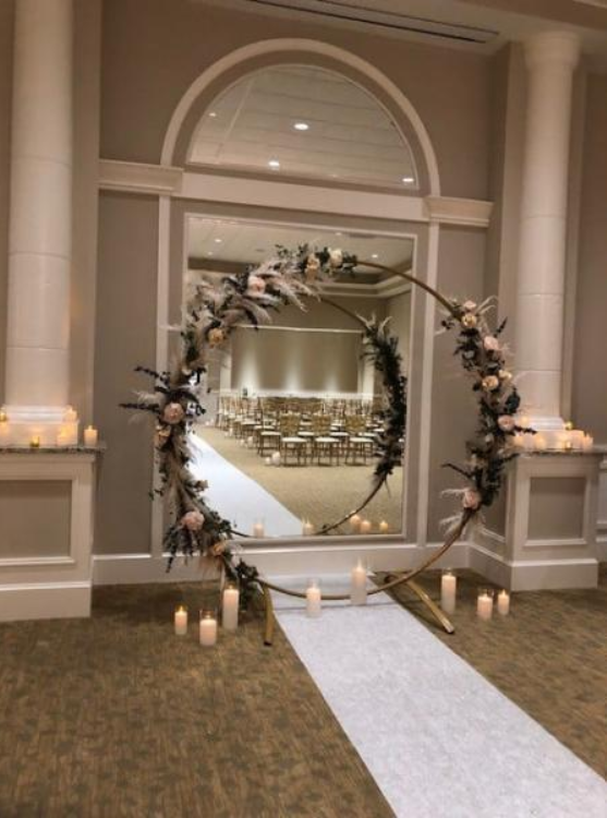 Floral circle arch framing a white aisle runner in an elegant indoor wedding venue