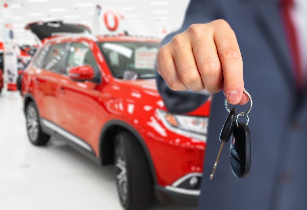 A Man is Holding a Car Key in Front of a Red Car — Loan Select Tablelands in Atherton, QLD