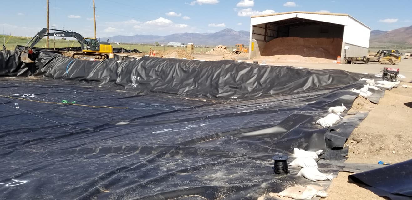 A large shed with dirt inside behind a lined area 