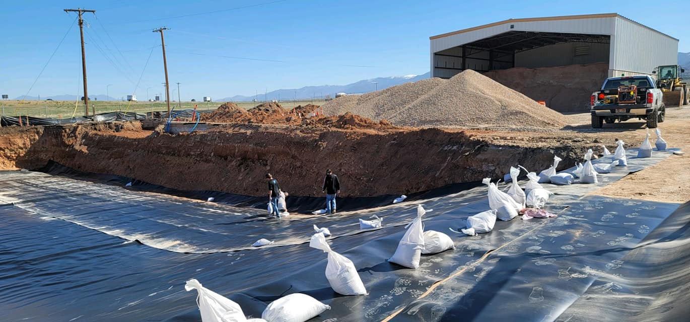 workers installing liner in a large area with a building in distance