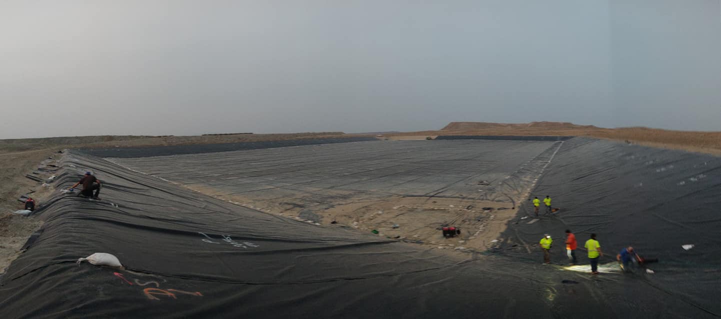 Large resevoir-sized are covered with black lining. Five workers installing in work apparel
