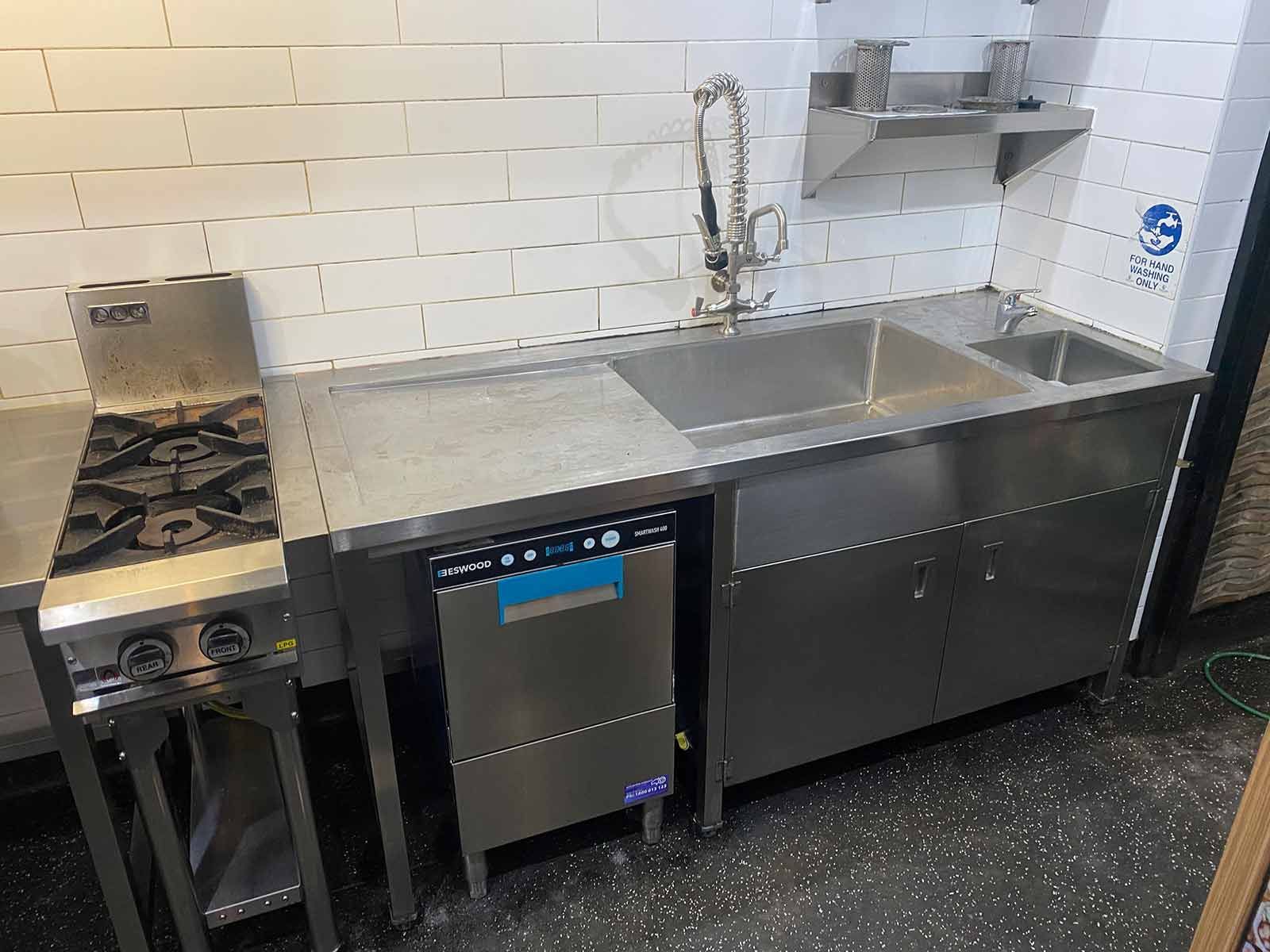 A New Commercial Kitchen With A Sink Dishwasher And Gas Stove — Lakesway Plumbing and Gas in Forster, NSW
