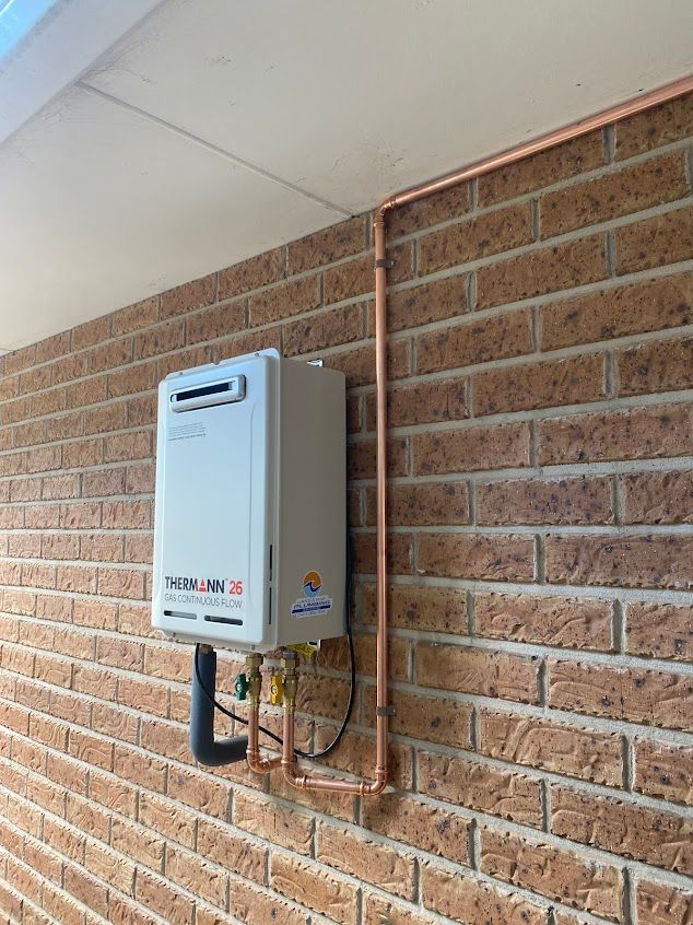 A Water Heater Is Installed on The Side of A Brick Building — Lakesway Plumbing and Gas in Forster, NSW