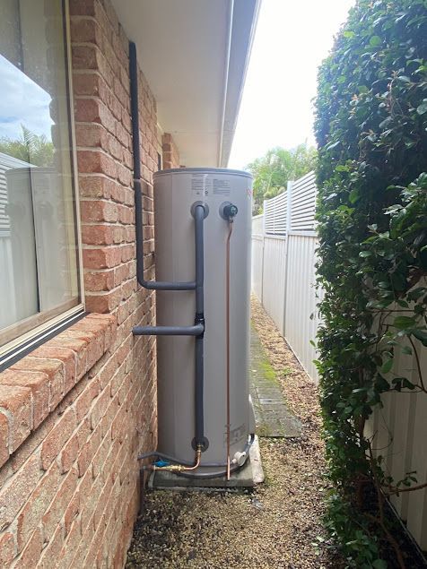 A Water Heater Is Attached to The Side of A Brick Building — Lakesway Plumbing and Gas in Forster, NSW