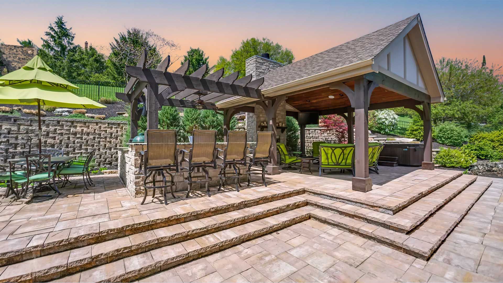 A patio with tables and chairs under a pergola and umbrellas.