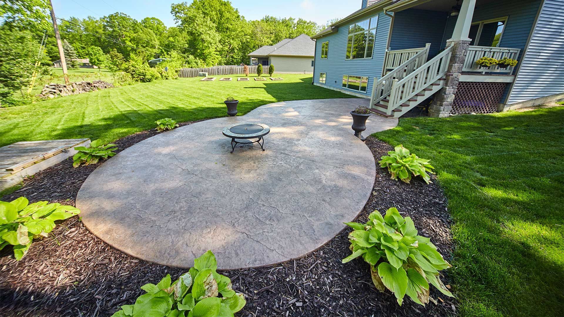 A patio with a fire pit in the middle of it in front of a house.