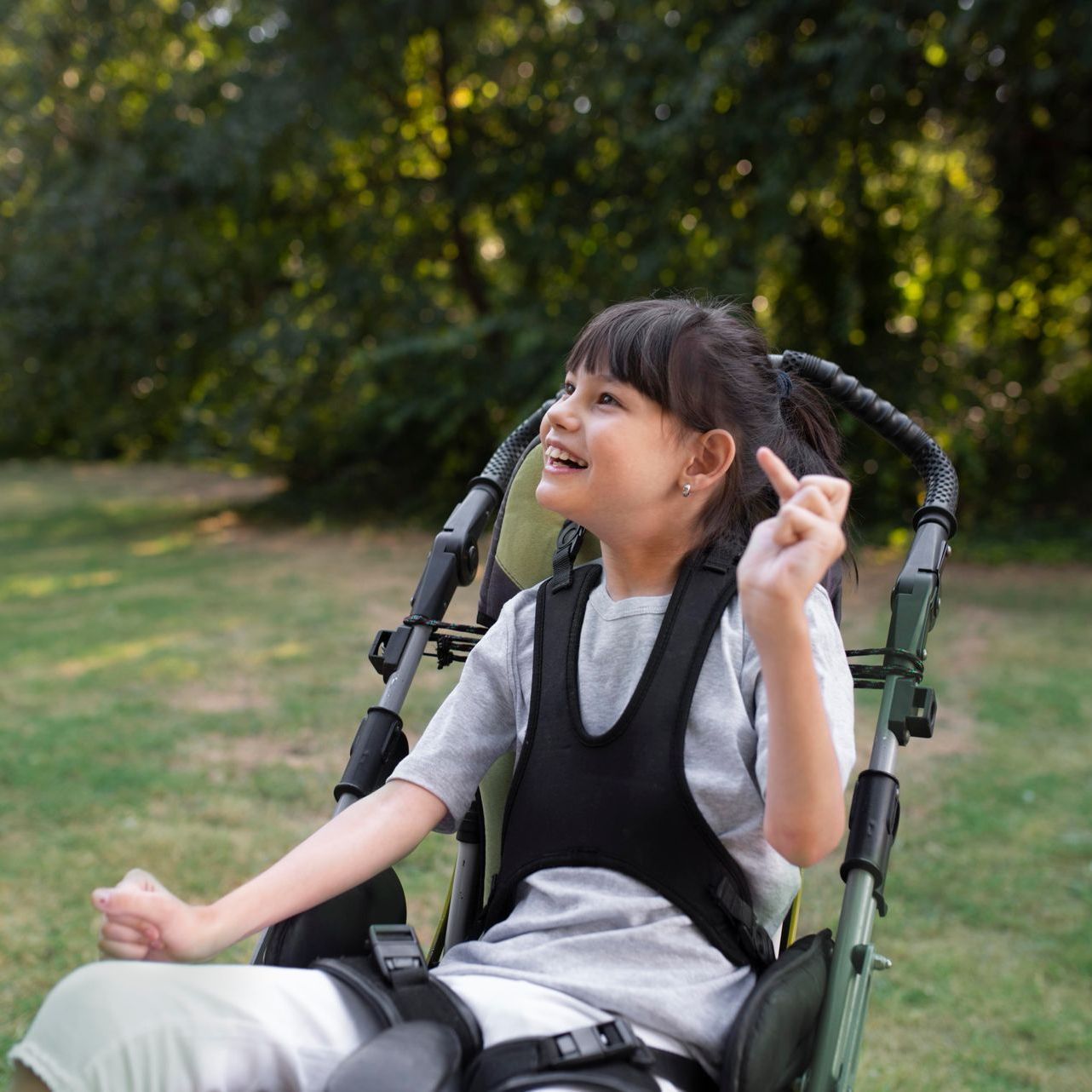 A young girl is sitting in a wheelchair and smiling.