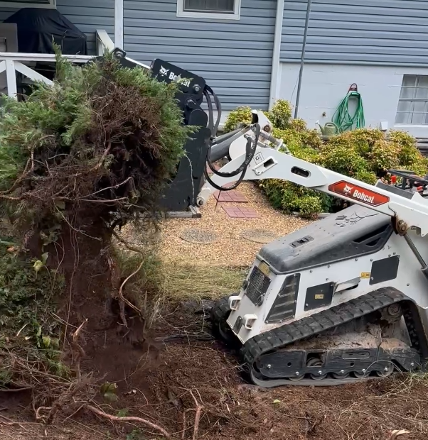 A bulldozer is digging a hole in the ground in front of a house.