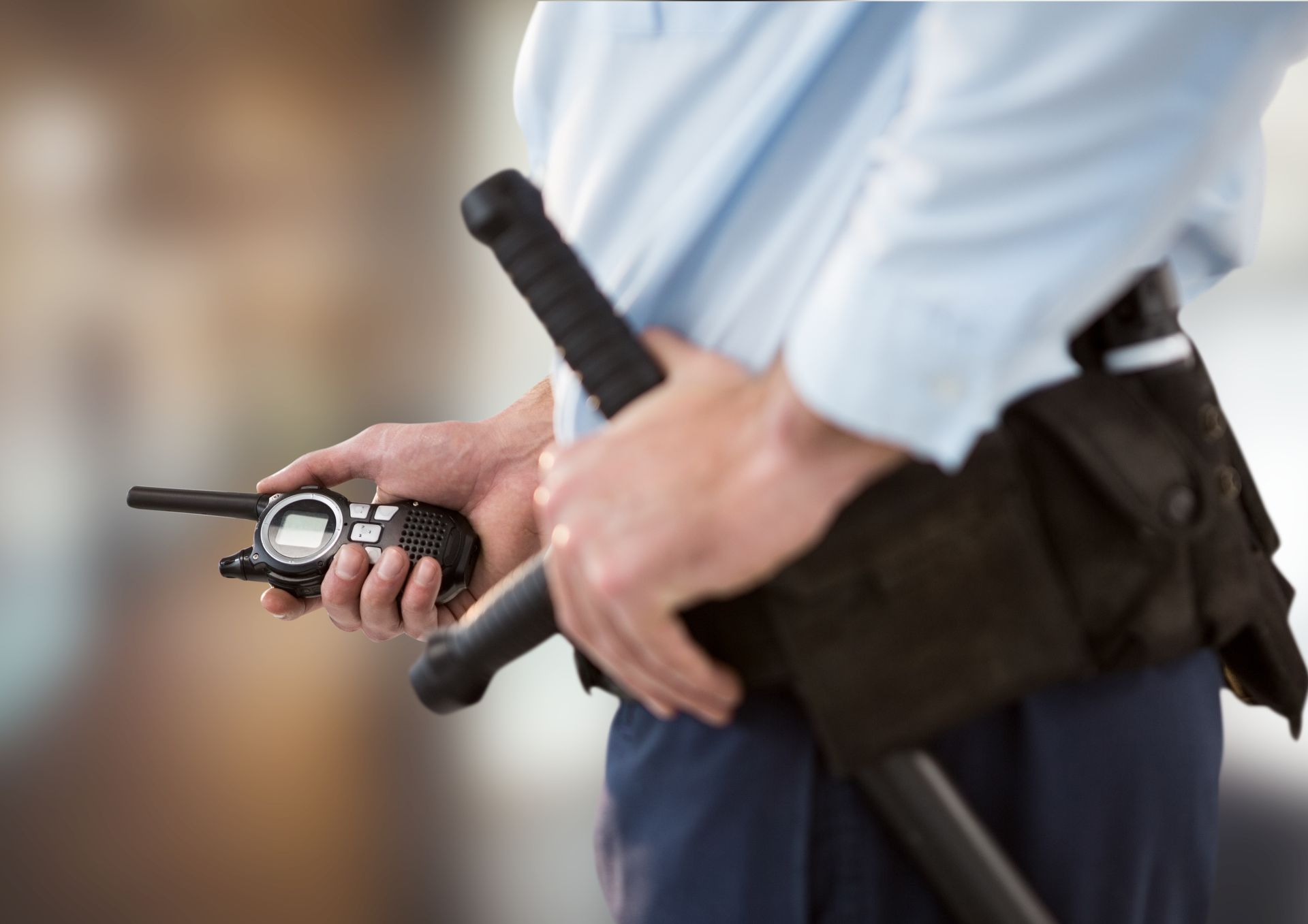 Police officer holding a walkie-talkie and baton on a blurred background