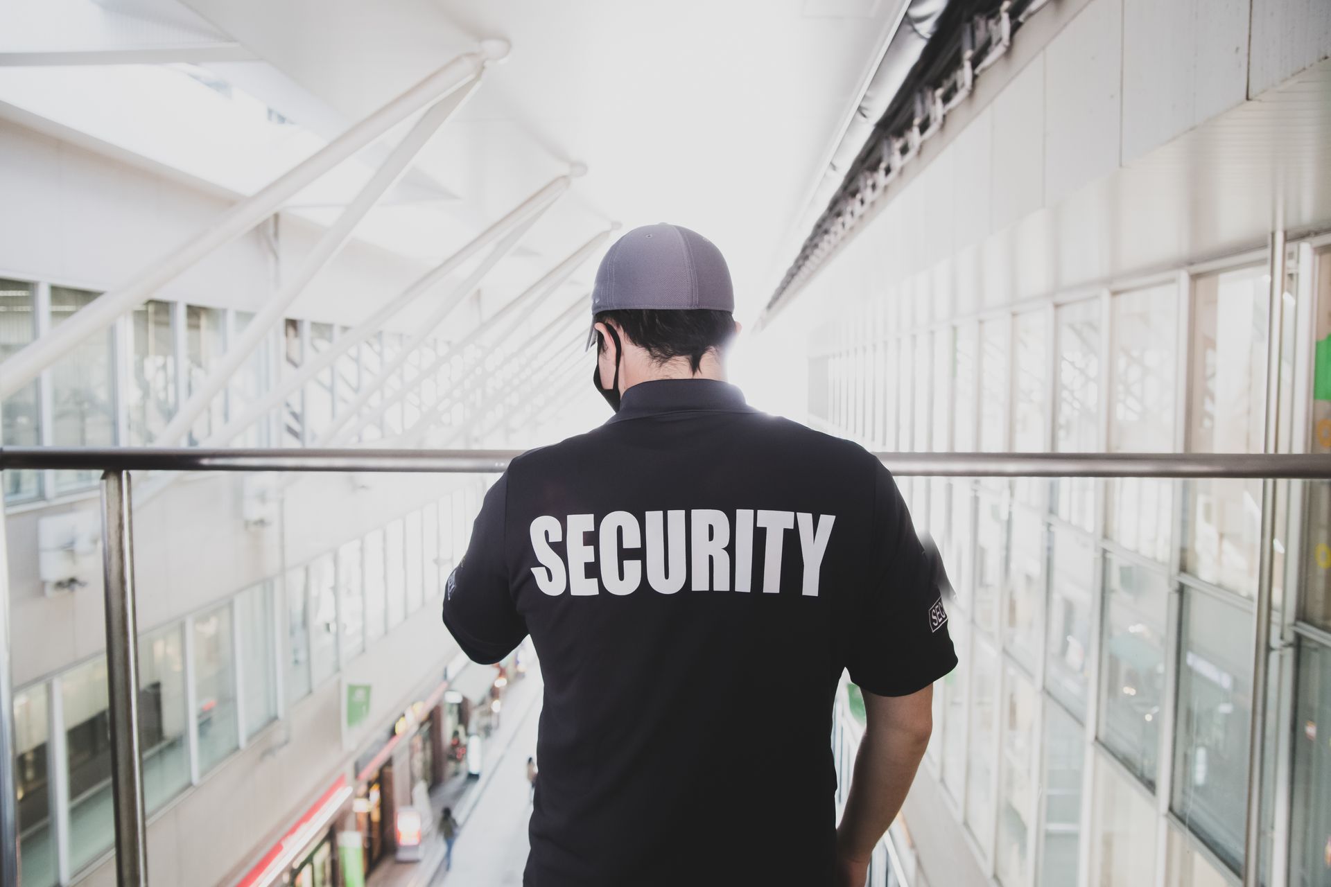 Security guard in black shirt and helmet walking along a bright indoor corridor.