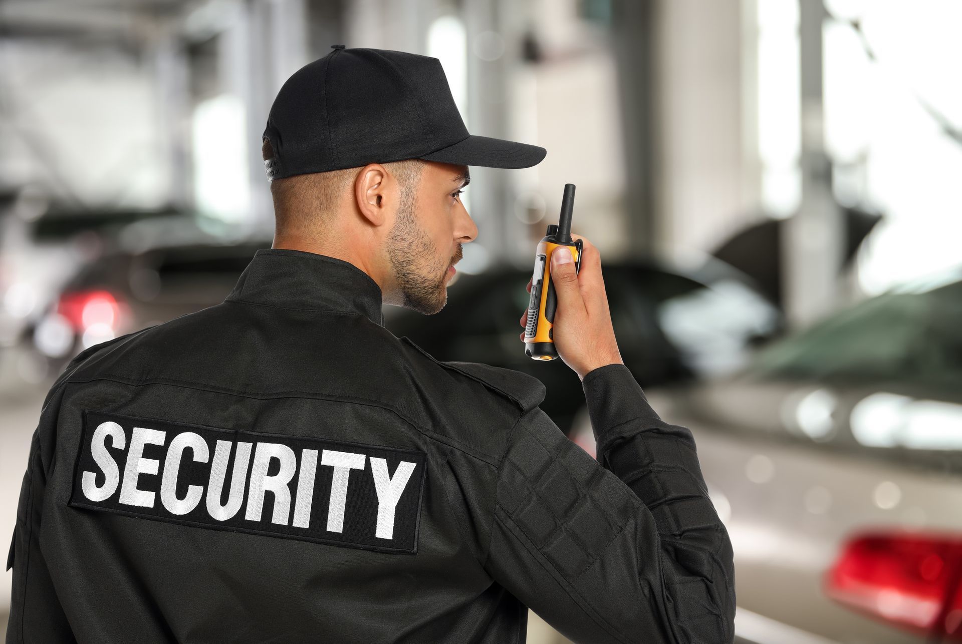Security guard in black uniform using a walkie-talkie in a parking garage