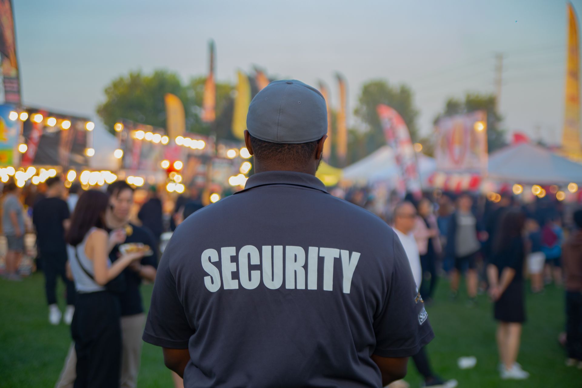 Security guard in dark shirt at a crowded outdoor festival at dusk