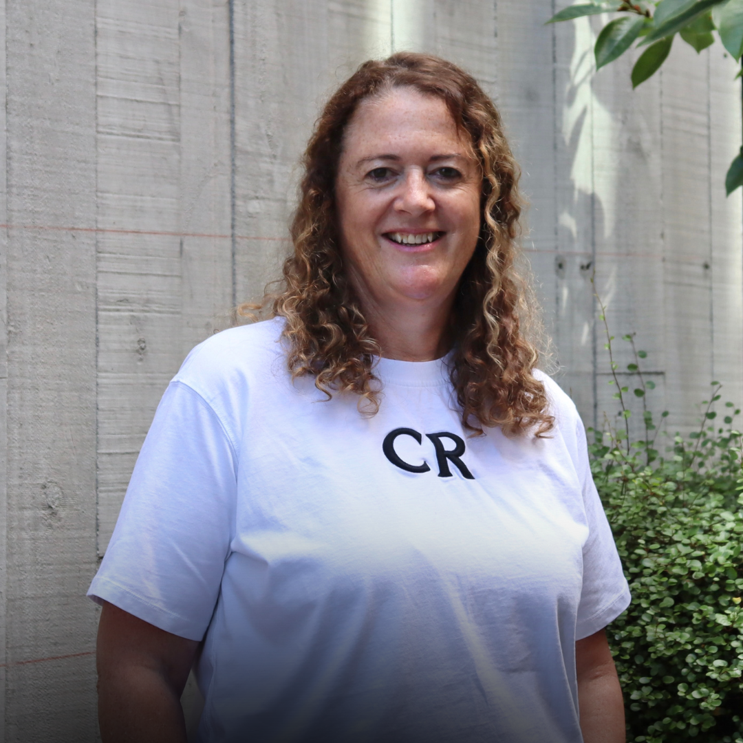 Woman with curly hair smiles in a white t-shirt with