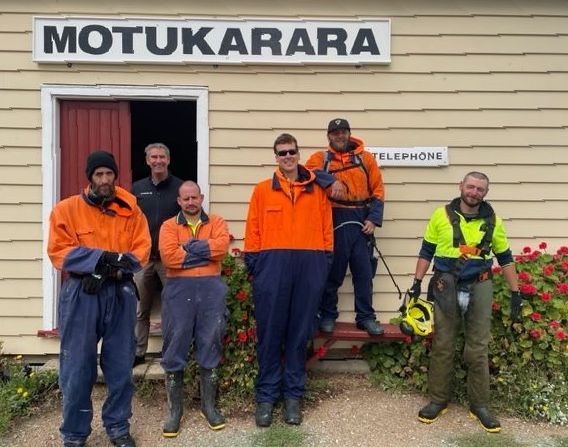 Group of workers in safety gear posing at a building with 