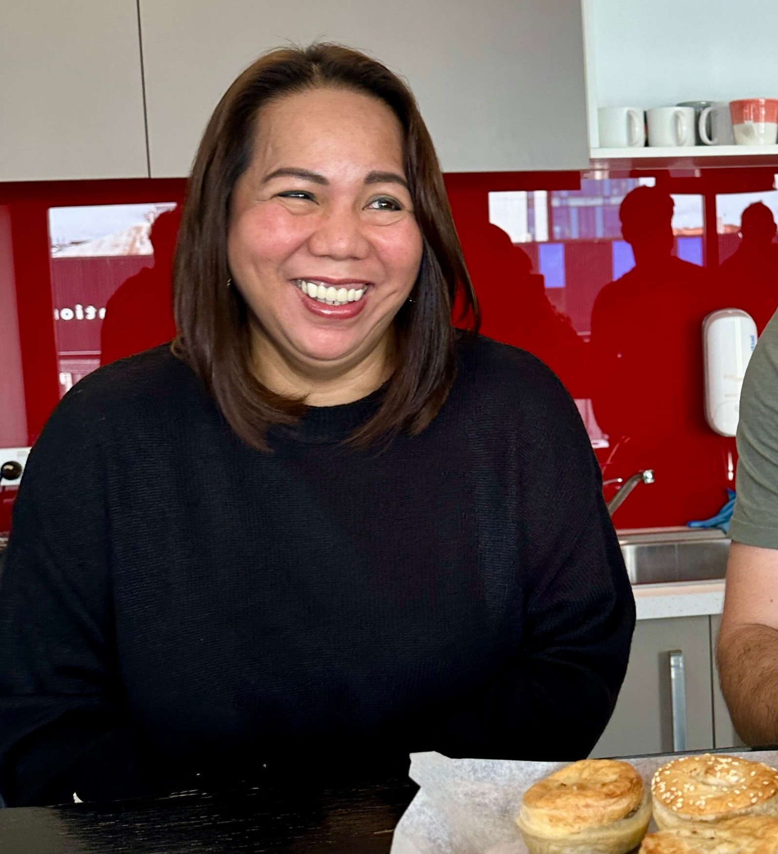 Smiling person at a table with pastries in a kitchen setting