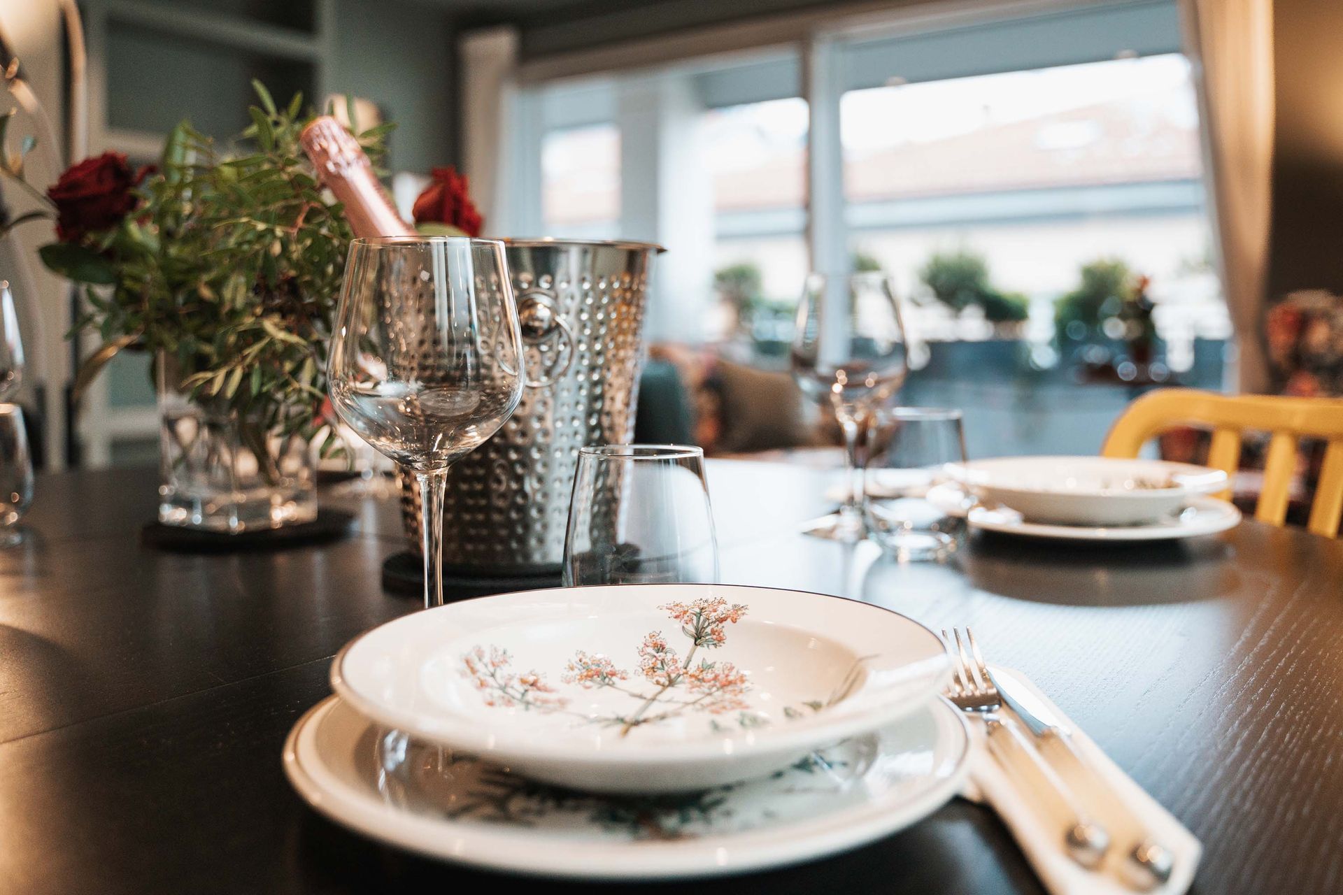 a table set with plates glasses and a bucket of champagne