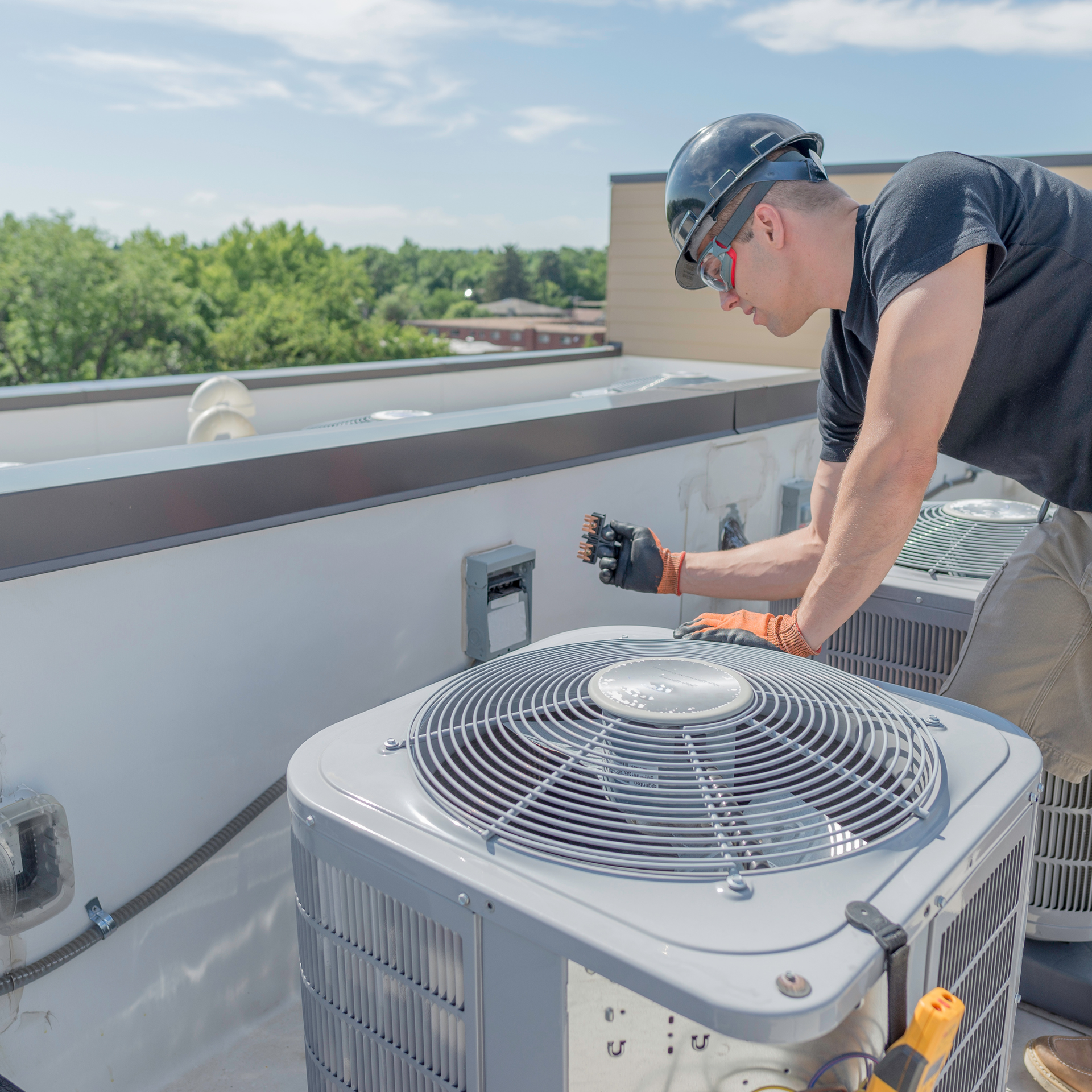 Air conditioning units with toolbox and gloves in backyard.
