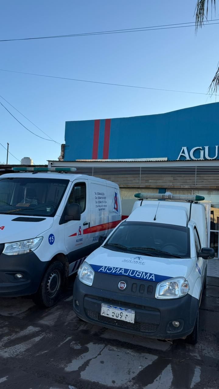 Dos furgonetas blancas aparcadas frente a un edificio azul bajo un cielo despejado.