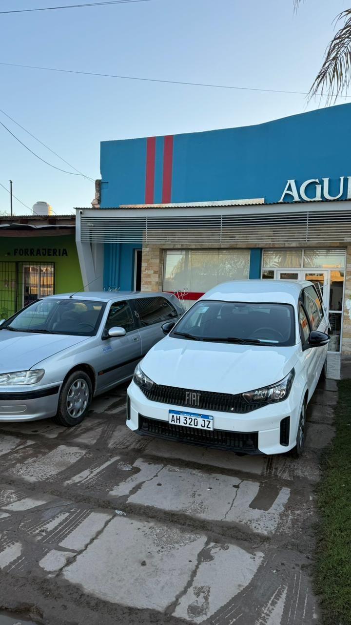 Dos coches aparcados delante de un edificio azul con rayas rojas y una entrada a una tienda.