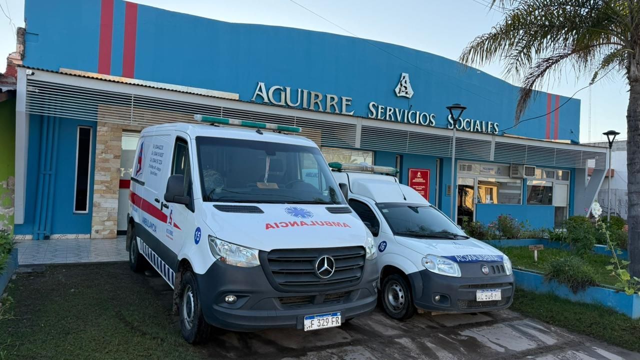 Dos furgonetas de reparto blancas aparcadas frente al edificio de Aguirre Services, de fachada azul.