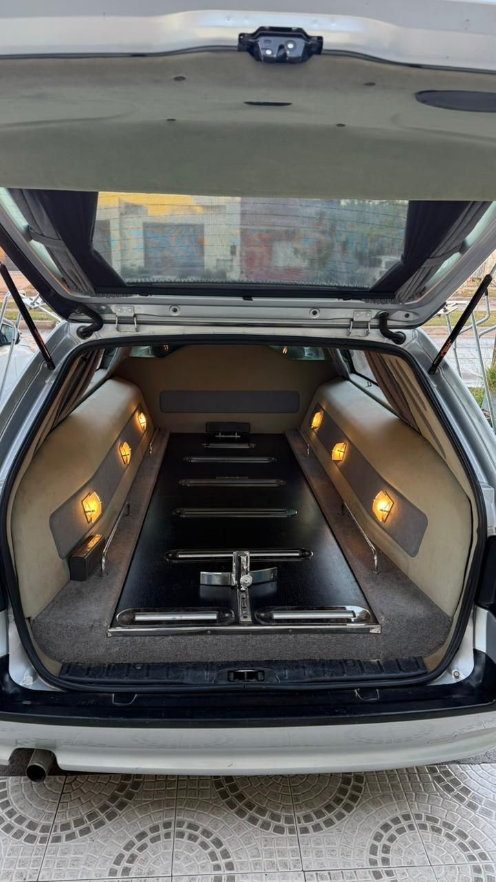 Maletero abierto de un SUV que deja ver una caja de audio negra personalizada con paneles laterales iluminados y un soporte central para el amplificador.