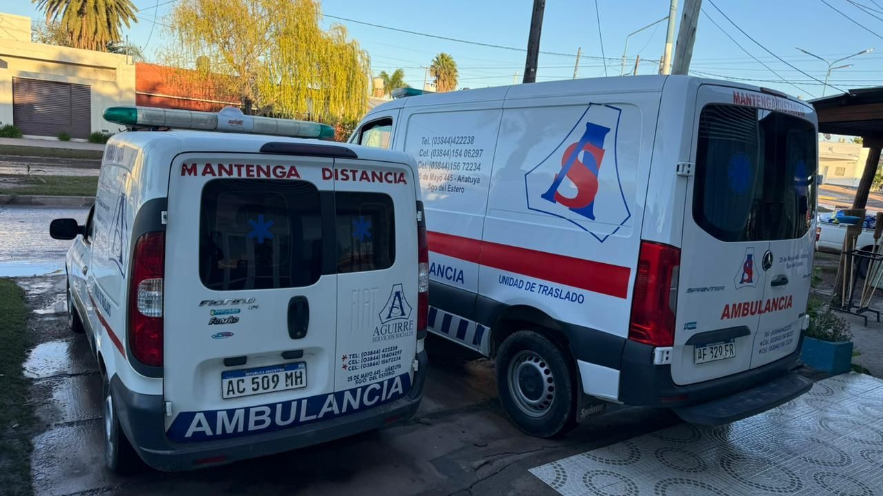 Dos ambulancias blancas aparcadas una al lado de la otra en una calle, con distintivos rojos de emergencia y una puerta trasera abierta.