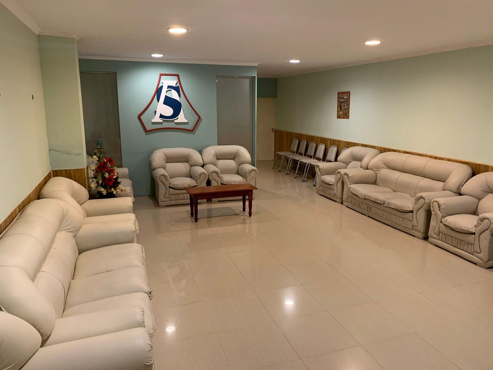 Luminoso salón en el sótano con sofás beige, suelo de baldosas y un cartel en la pared con un “5” azul.