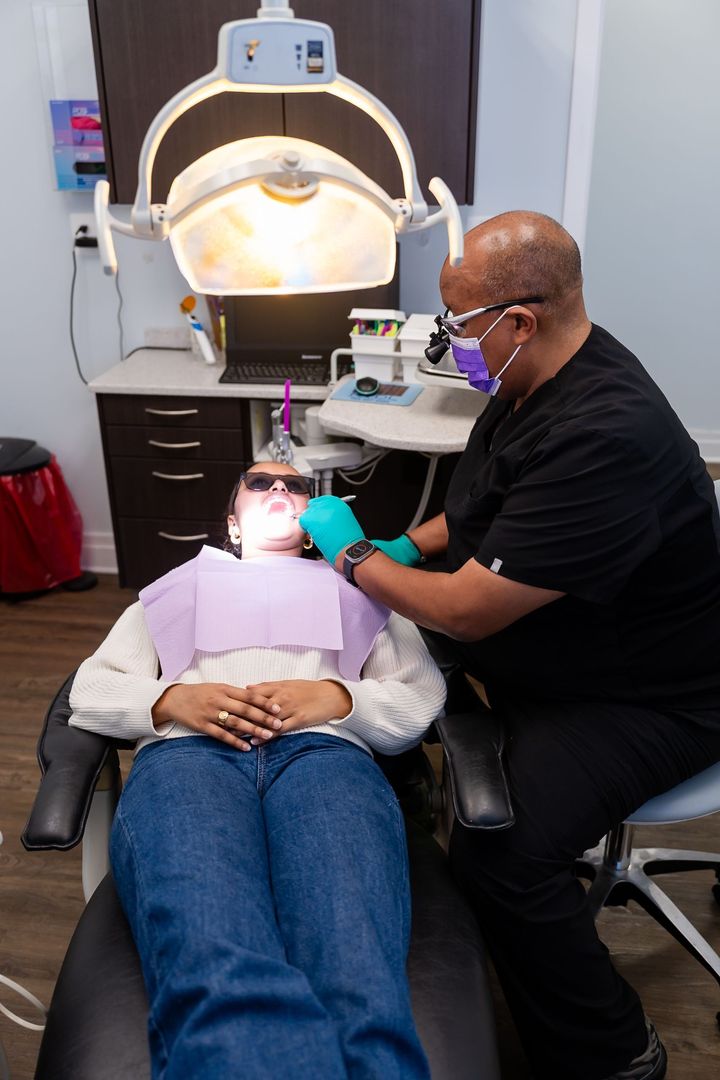 Dentist examining a patient's mouth with tools in a dental office.