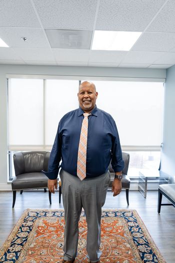 Man wearing a blue shirt and tie standing in an office.